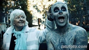 Фото тату человека, полностью покрытого татуировками в стиле зомби, рядом с пожилой женщиной. Реалистичный рисунок татуировки с изображением костей и гниющих тканей.